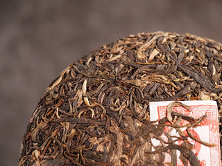 Close-up of the front side of 2019 Qilin Tribute Sheng Pu-erh Tea Cake – Ancient Arbor 357g, showing detailed ancient arbor tea leaf strands and golden buds.