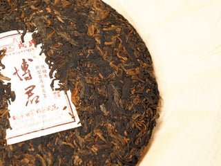 Close detail of the right half of the 2020 Bojun 500g cake, displaying the tightly pressed dark fermented leaves with golden tips.