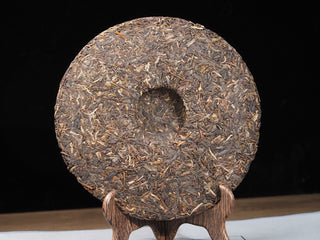 Back view of unwrapped 2021 Dayi Guanchao raw puerh tea cake Batch 2101, showing the classic compression dimple (wo tou).
