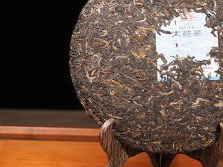 Detailed close-up showing the edge and compression texture of the 2021 Dayi Mi Xiang Raw Puerh tea cake.
