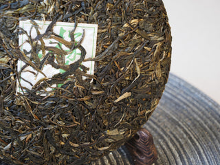 2025 Tan Chun raw Puerh tea cake displayed with its embedded inner certification ticket.
