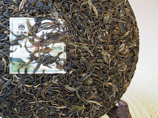 2026 Tan Chun raw Puerh tea cake displayed with its embedded inner certification ticket.