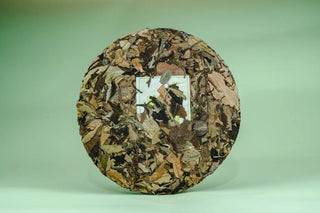 Back side of the compressed Shou Mei tea cake revealing the natural texture of sun-dried white tea leaves.