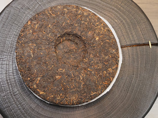 The back side of the 2019 Dayi 7572 ripe puerh tea cake, displaying the traditional circular compression dimple in the center.