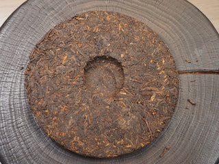 The back side of 2019 Dayi 7592 ripe puerh tea cake, showing the deep central indentation from traditional compression.