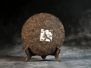 Front view of Bulang Mountain Ancient Tree Ripe Pu-erh tea cake without any packaging, displaying neat and dark tea leaves