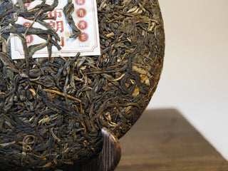 Side profile of compressed Bulang Mountain raw pu-erh tea cake showing leaf thickness