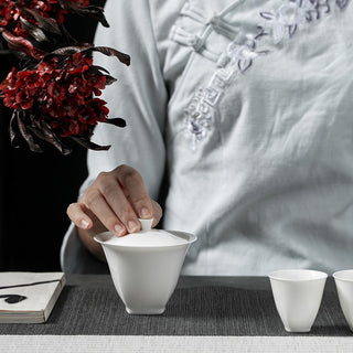 Authentic Gongfu tea brewing setup featuring white porcelain gaiwan on tea mat