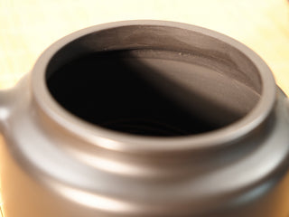 Close-up of the Heini Dezhong Yixing teapot rim and opening, smooth raw black clay surface on a bamboo mat