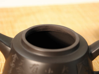 Close-up of Black Zhu Ni Shede Yixing teapot rim, looking into the dark interior with engraved body and handle at edges