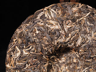 Detailed view of unwrapped Sheng Iron Fire Lao Man'e raw Puerh cake showcasing the premium dry old-tree leaves and silver tips.