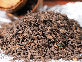 Close-up texture of aged Menghai ripe Pu-erh loose tea leaves ready for brewing.