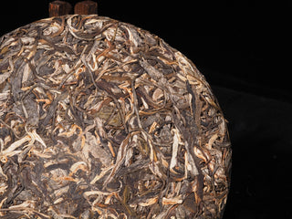 Detailed profile of a stone-pressed raw Puerh tea cake displaying hand-selected uniform spring leaves.