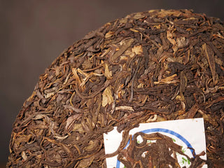Close-up of the front side of Value Classic 2008 Tribute Sheng Pu-erh Tea Cake – 357g Menghai (2019 Pressed), highlighting tea leaves and texture