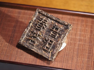 Front view of Yunnan Raw Pu-erh Waffle Cake – Three Legendary Leaves brick, showing Chinese characters Chunming Pu-erh