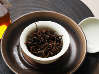Gong Fu Cha brewing setup featuring Yunnan Shaken-Leaf Black Tea leaves, a gaiwan, and a tasting cup.
