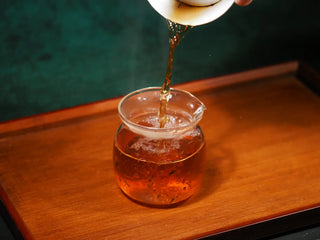 Pouring the deep, rich amber liquor of YXT Jingyang Golden Flower Fu Tea Special Grade 300g into a clear glass cup during the brewing process.