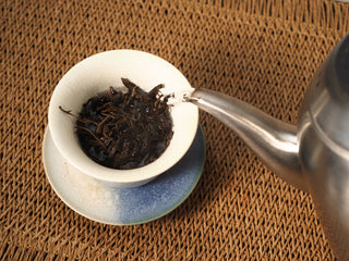 Kettle pouring boiling water over Jing Chang Hao Bada Ancient Trees 2013 raw Pu-erh leaves in a gaiwan for the rinse