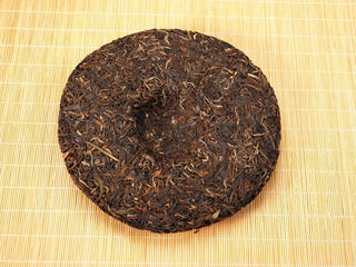 Back of Jing Chang Hao Mengsong Autumn Harvest 2013 raw Pu-erh cake showing the center dimple and well-built compressed leaves