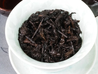 Wet tea leaves (wet spent leaves) of 2014 Liubao Dark Tea in a gaiwan after brewing, showing leaf thickness and rich color.