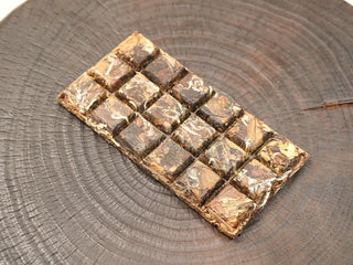 Top view of 2014 sun-dried Fuding White Peony 100g waffle cake scored into 18 sections, dark aged leaves pressed firmly.