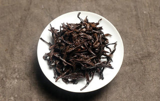 Wet leaf of 2017 Bojun Ripe Pu-erh after multiple steepings, dark brown fermented leaves in a white porcelain dish.