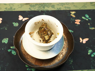 2018 indoor-withered Fuding White Peony biscuit steeping in a ceramic gaiwan, leaves slowly unfurling in hot water.