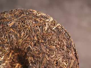 Close-up of the back side of 2019 Qilin Tribute Sheng Pu-erh Tea Cake – Ancient Arbor 357g, focusing on leaf compression and natural tea texture.