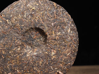 The back of the 2021 Dayi Mi Xiang Raw Puerh tea cake, showing the traditional central dimple indentation.
