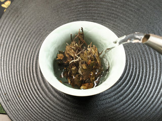Hot water being poured into a gaiwan over 2021 sun-dried Fuding Shou Mei tea leaves from the 50g mini cake.