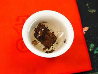 2024 Shou Mei and Chen Pi waffle cake section steeping in a gaiwan, leaves beginning to unfurl in hot water.