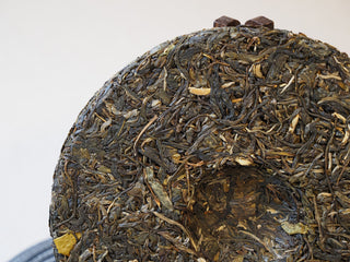 Side angle showing the thickness and clean compression edge of the 2025 Tan Chun raw Puerh tea cake.