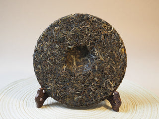 Side angle showing the thickness and clean compression edge of the 2026 Tan Chun raw Puerh tea cake.