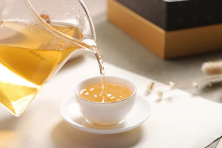 Pouring the bright, clear infusion of 2019 Lincang Ancient Tree Raw Pu-erh Tea into a white teacup.