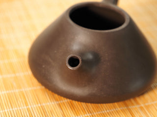 Close-up of the spout opening of a Fengming Ziye Shipiao Yixing teapot, dark Shihuang clay body on a bamboo mat