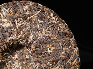 Macro texture of the 2023 Lao Man'e raw Puerh cake displaying handcrafted quality and ancient tree leaf structure.