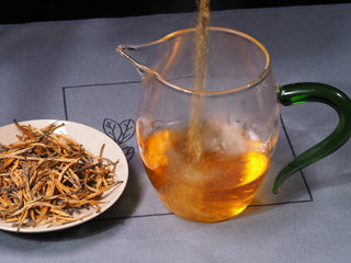 Pouring brewed Golden Buds Classic Dianhong Black Tea into glass pitcher