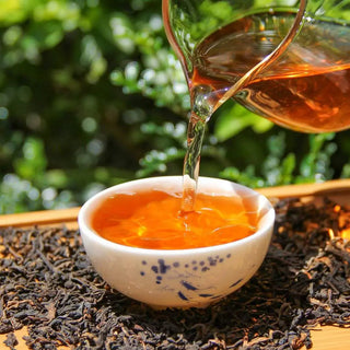 Pouring bright amber-red rose scented ripe puerh tea into a white teacup, showcasing clarity.