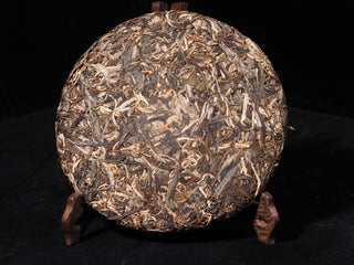 Full view of unwrapped Sheng Bulang Buds Puerh tea cake showcasing premium unblended single-origin tea leaves.