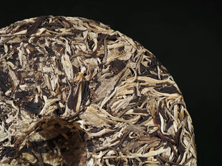 Detailed close-up of the back of Yunnan Jinggu White Peony Tea Cake 357g, emphasizing silver-wrapped jade quality