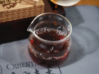 Ripe Pu-erh tea liquor from the Yunnan Mini Pu-erh Tea Brick being poured from a gaiwan into a glass gongdao cup.