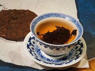 Steeping stage of Yunnan Red Glow Ripe Pu-erh Tea Mini Cake – 100g in gaiwan, with tea leaves fully unfurling in the red-glow liquor.
