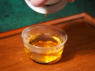 Bright golden-orange tea liquor from brewed YXT Jingyang Golden Flower Fu Tea First Grade 300g in a clear glass cup.