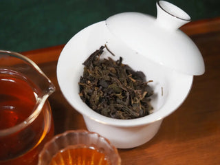 Wet, fully expanded dark tea leaves of YXT Jingyang Golden Flower Fu Tea Special Grade after brewing, showcased in a white strainer.