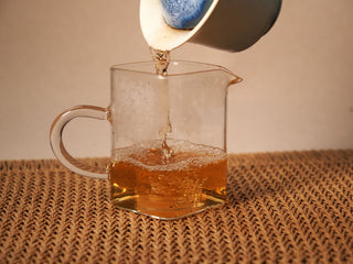 Golden amber liquor of Jing Chang Hao Bada Ancient Trees 2013 raw Pu-erh poured into a glass fairness pitcher