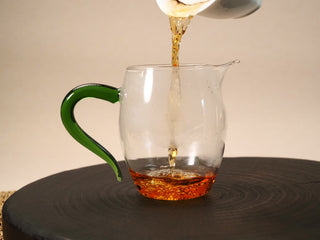 2013 Fuding Shou Mei tea poured into a glass pitcher with a green glass handle, the liquor a bright clear red.