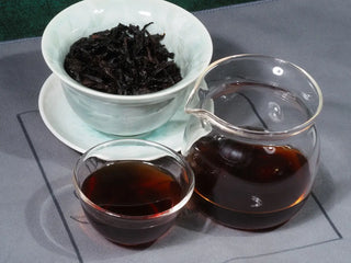 A complete tea set setup for serving 2014 Aged Liubao Dark Tea, showing the liquor, wet leaves, and cups ready for tasting.