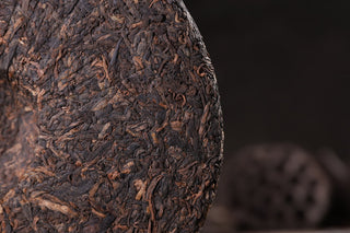 Back of the 2019 Bojun 500g cake without inner ticket, showing the tightly pressed dark fermented leaves with golden tips.