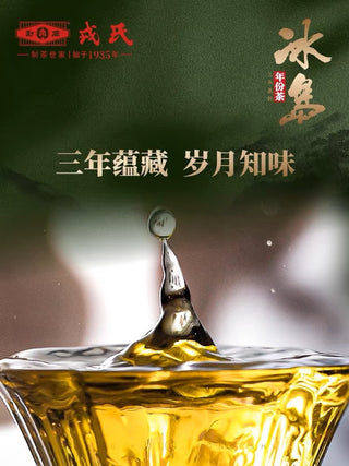 A water drop splashing into a glass of golden Bingdao raw pu-erh tea, with the Mengku Rongshi brand mark.