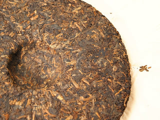 Back of the 2020 Bojun 500g cake, showing tightly pressed dark fermented leaves with golden tips on a light background.